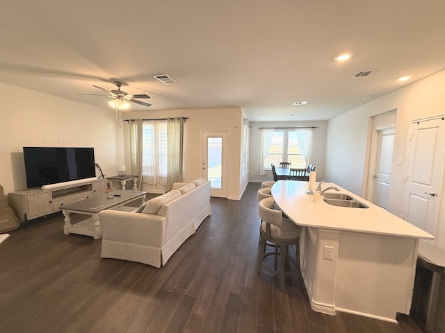 living room featuring dark hardwood / wood-style floors, ceiling fan, and sink