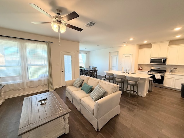 living room with ceiling fan, sink, and dark hardwood / wood-style floors