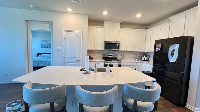 kitchen with backsplash, white cabinets, an island with sink, and stainless steel appliances