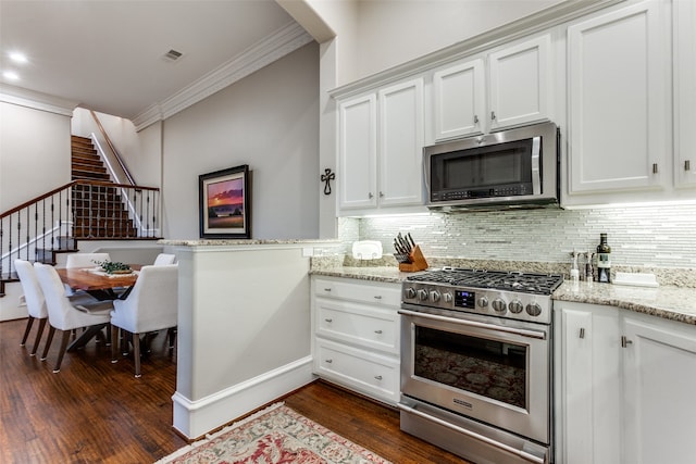 kitchen featuring dark wood-type flooring, crown molding, light stone countertops, appliances with stainless steel finishes, and white cabinetry