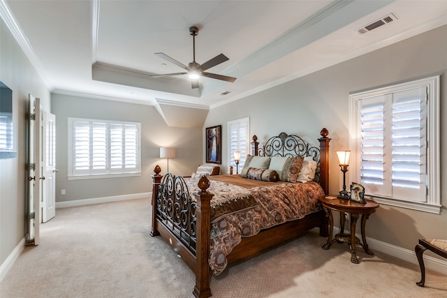 carpeted bedroom with ceiling fan, a raised ceiling, and ornamental molding