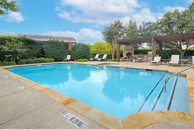 view of pool featuring an outdoor stone fireplace, a patio area, and a pergola