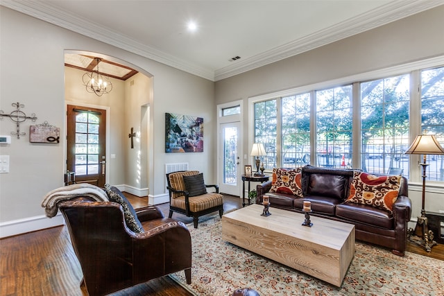 living room with a chandelier, hardwood / wood-style floors, a wealth of natural light, and crown molding