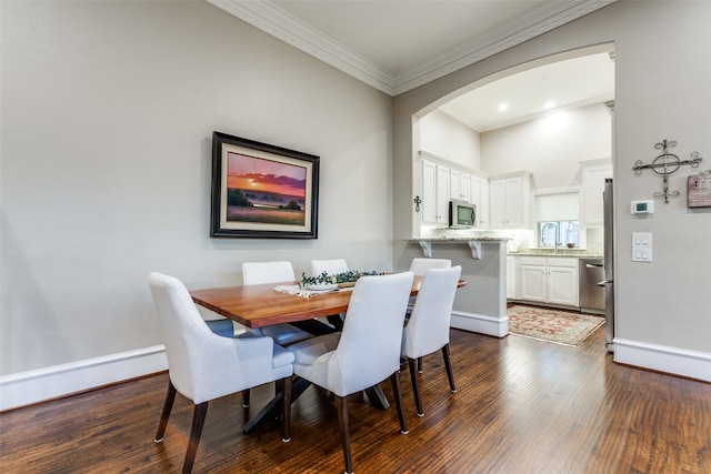 dining space featuring dark hardwood / wood-style floors, sink, and crown molding