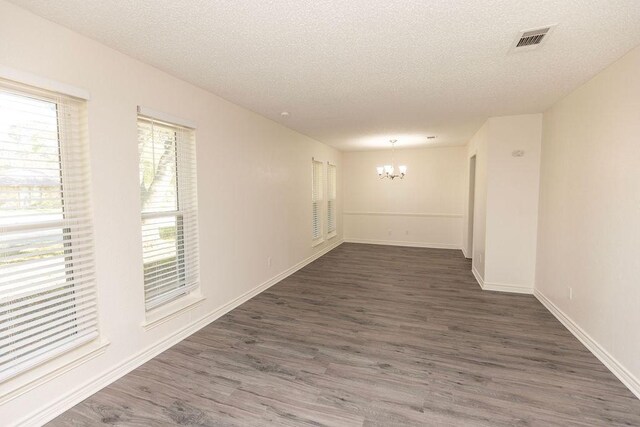 corridor with dark hardwood / wood-style flooring, a textured ceiling, and a chandelier