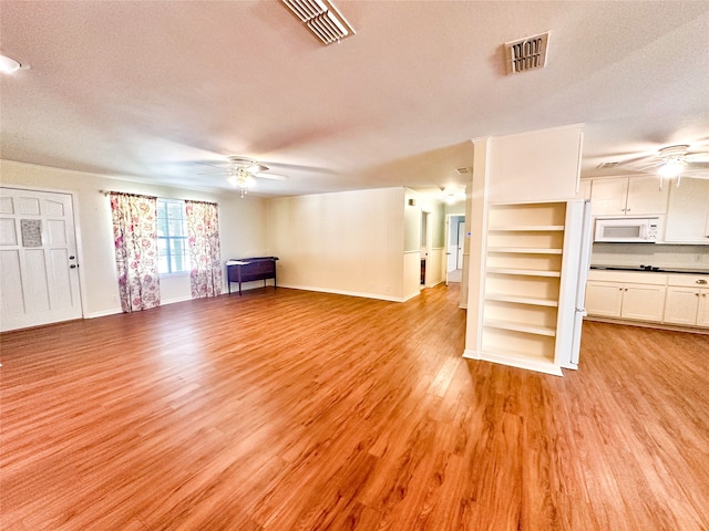 unfurnished living room with a textured ceiling, light hardwood / wood-style flooring, and ceiling fan