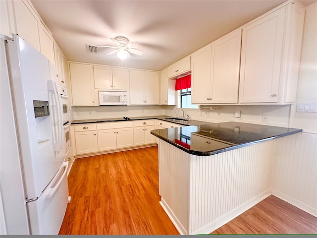 kitchen with kitchen peninsula, white cabinetry, sink, and white appliances