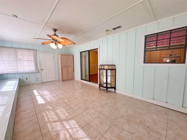 tiled spare room with ceiling fan and wood walls