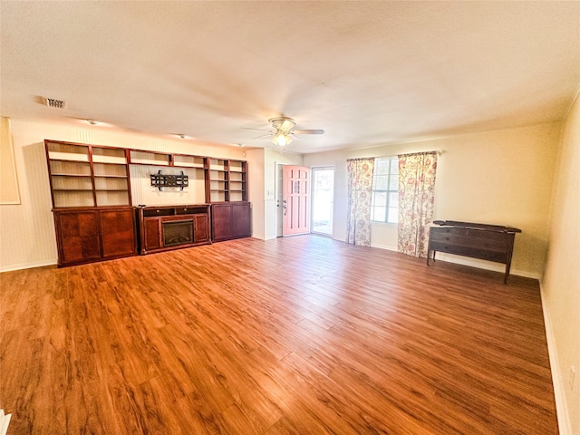 unfurnished living room with hardwood / wood-style flooring, ceiling fan, and a textured ceiling