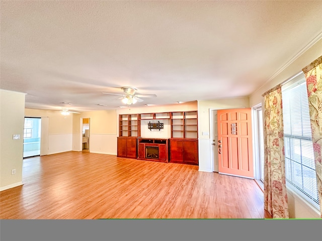 unfurnished living room with ceiling fan, light wood-type flooring, and a textured ceiling