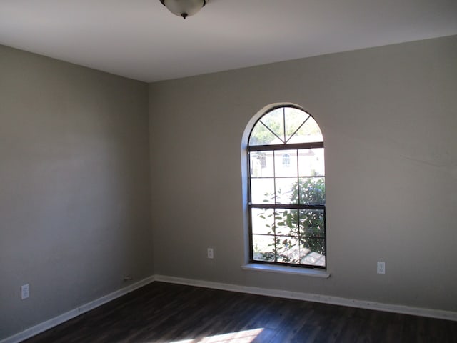 empty room with dark wood-type flooring and a healthy amount of sunlight