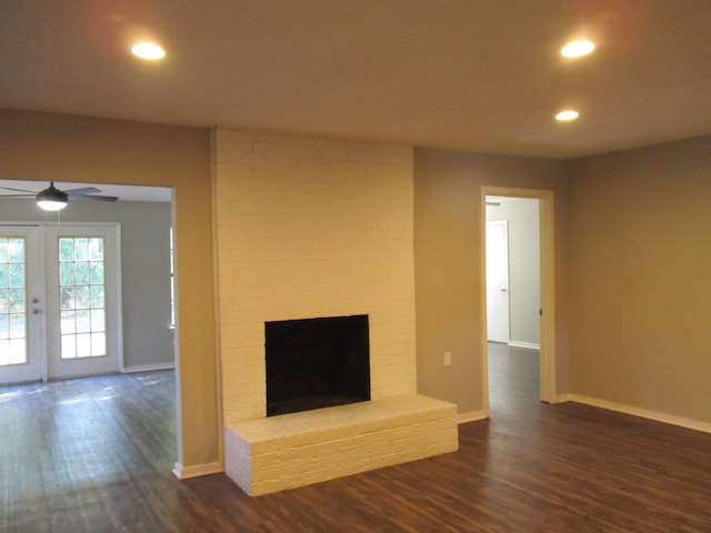 unfurnished living room featuring ceiling fan, french doors, dark hardwood / wood-style floors, and a brick fireplace