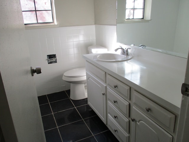 bathroom with tile patterned flooring, vanity, a healthy amount of sunlight, and tile walls