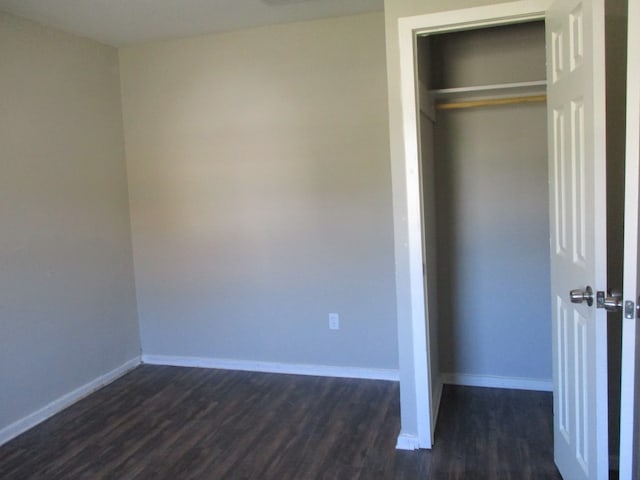 unfurnished bedroom featuring dark hardwood / wood-style flooring and a closet