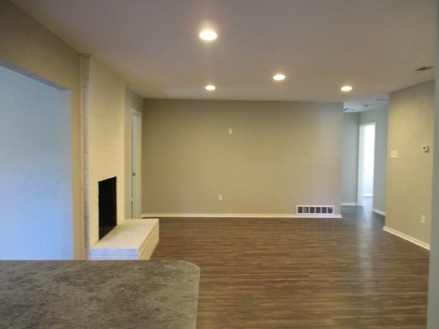 unfurnished living room with dark hardwood / wood-style flooring and a brick fireplace