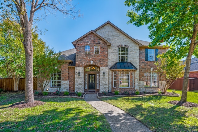 view of front of house with brick siding, a standing seam roof, fence, and a front yard