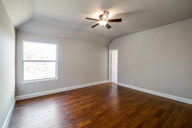 unfurnished room featuring lofted ceiling, dark wood-style flooring, and baseboards