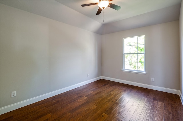 empty room with dark wood finished floors, a ceiling fan, and baseboards