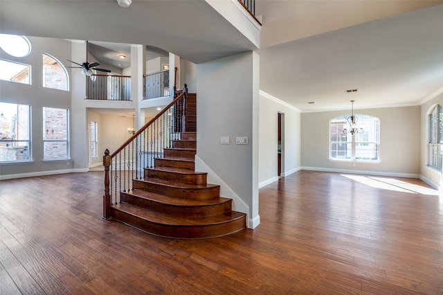 stairway with ornamental molding, wood-type flooring, and a high ceiling