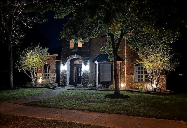 view of front facade featuring a front yard, stone siding, and brick siding