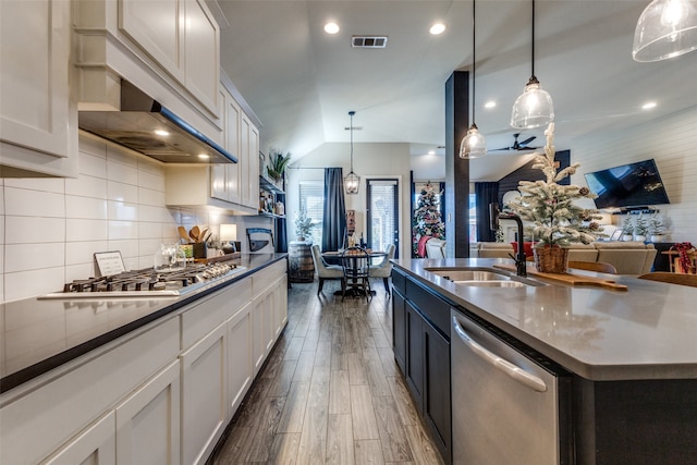 kitchen featuring stainless steel appliances, sink, decorative light fixtures, white cabinets, and an island with sink