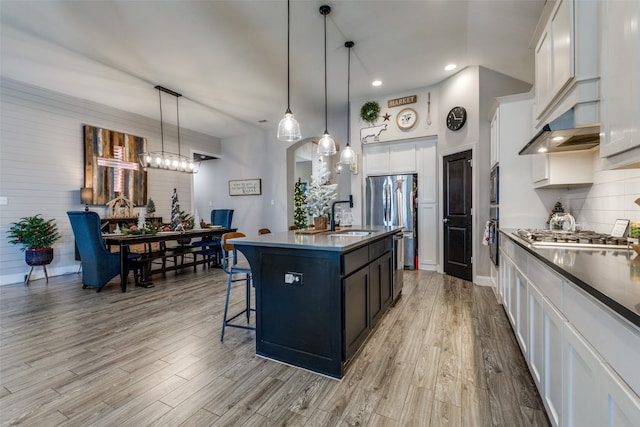 kitchen with white cabinetry, sink, decorative light fixtures, a center island with sink, and appliances with stainless steel finishes