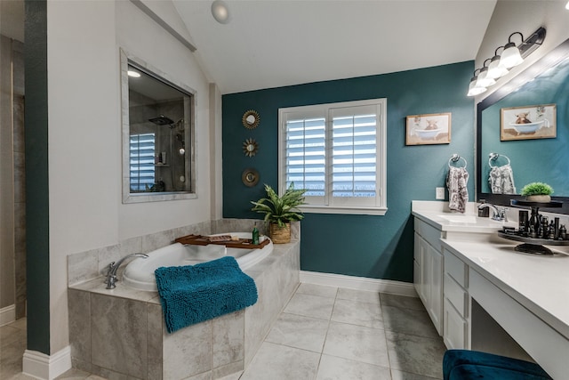 bathroom with tile patterned floors, vanity, tiled bath, and vaulted ceiling