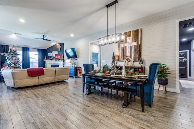 dining space with ceiling fan, wooden walls, and light hardwood / wood-style floors