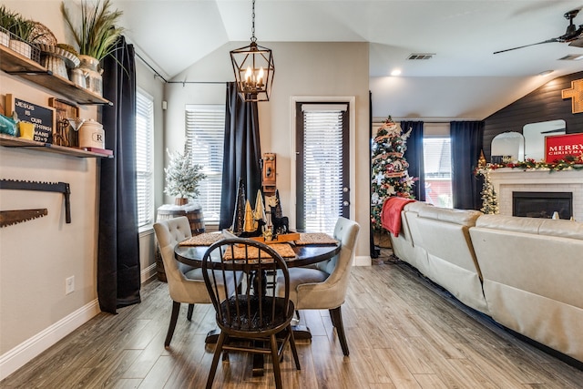 dining space featuring hardwood / wood-style floors, a fireplace, a wealth of natural light, and vaulted ceiling