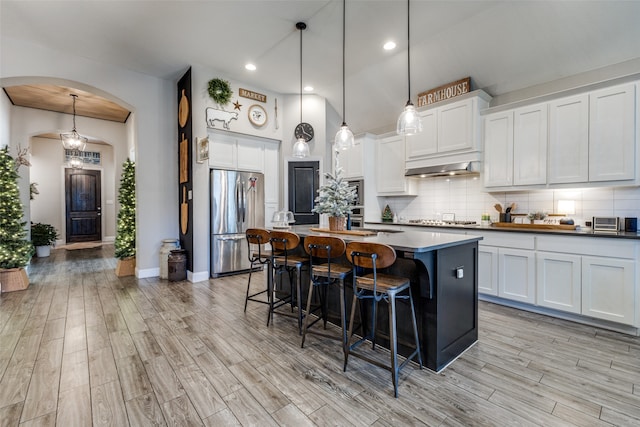 kitchen featuring pendant lighting, light hardwood / wood-style flooring, appliances with stainless steel finishes, white cabinetry, and a breakfast bar area