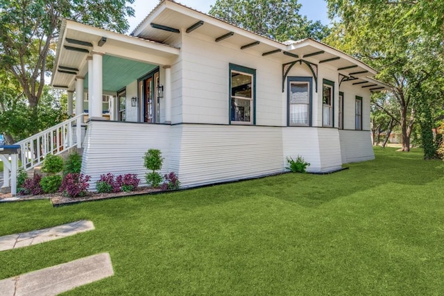 view of side of home with a porch and a yard