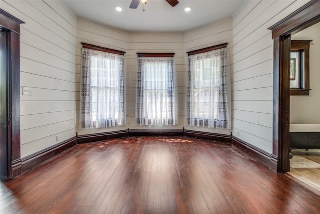 unfurnished room featuring ceiling fan, dark wood-type flooring, and a wealth of natural light