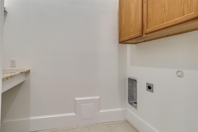 washroom with light tile patterned floors, cabinets, and hookup for an electric dryer