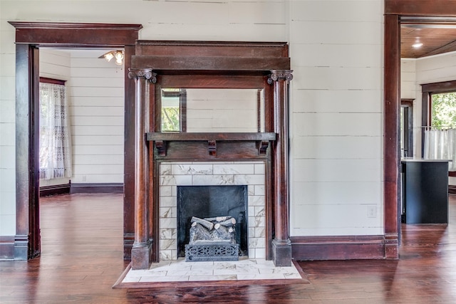 unfurnished living room featuring wooden walls, dark hardwood / wood-style floors, and a tile fireplace