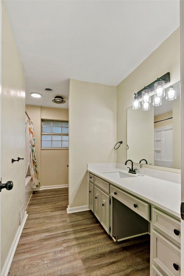 bathroom featuring wood-type flooring, vanity, and shower / bathtub combination with curtain