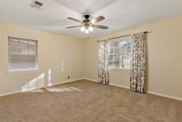 carpeted spare room featuring ceiling fan and a wealth of natural light