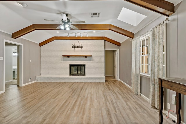 unfurnished living room featuring ceiling fan, lofted ceiling with skylight, light hardwood / wood-style flooring, and a brick fireplace