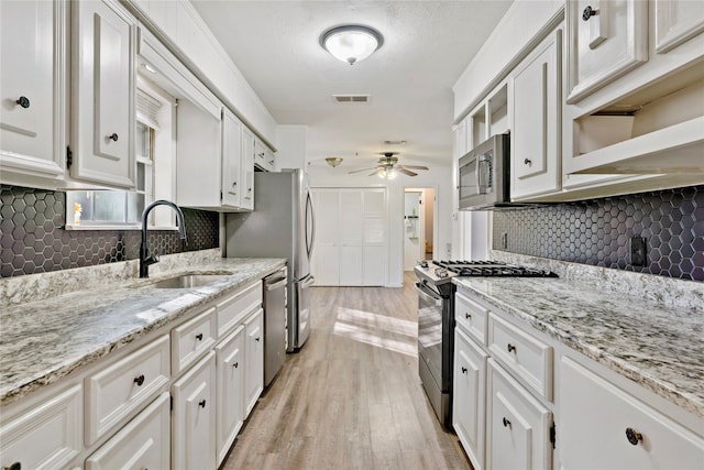 kitchen with appliances with stainless steel finishes, light hardwood / wood-style floors, white cabinetry, and sink