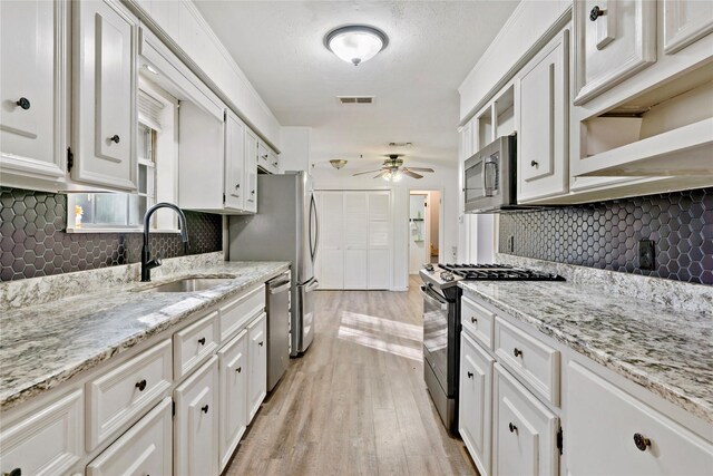 2680 Hubbard St, Paris, TX 75460 - kitchen with stainless steel appliances, a sink, ceiling fan, light wood-style flooring, and white cabinets