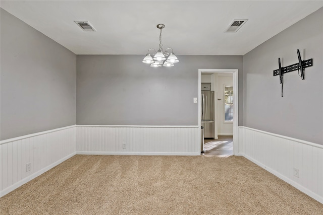 carpeted spare room with a notable chandelier