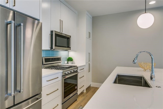 kitchen featuring sink, white cabinets, decorative light fixtures, and appliances with stainless steel finishes