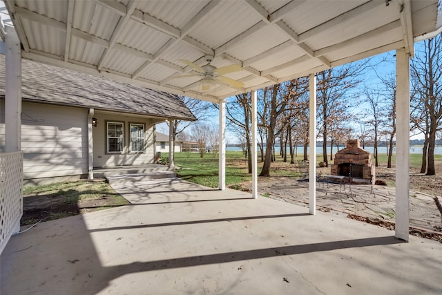 view of patio with ceiling fan, a water view, and exterior fireplace