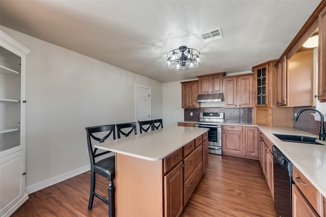 kitchen featuring dishwasher, stainless steel range, a center island, wood-type flooring, and a breakfast bar area