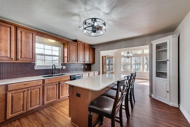 kitchen with a kitchen island, wood-type flooring, sink, and an inviting chandelier