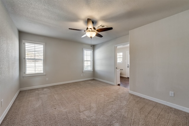 carpeted spare room featuring ceiling fan, a healthy amount of sunlight, and a textured ceiling