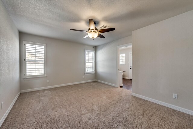 carpeted spare room featuring ceiling fan, a healthy amount of sunlight, and a textured ceiling