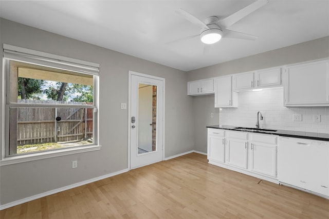 kitchen with tasteful backsplash, white dishwasher, sink, white cabinets, and light hardwood / wood-style floors