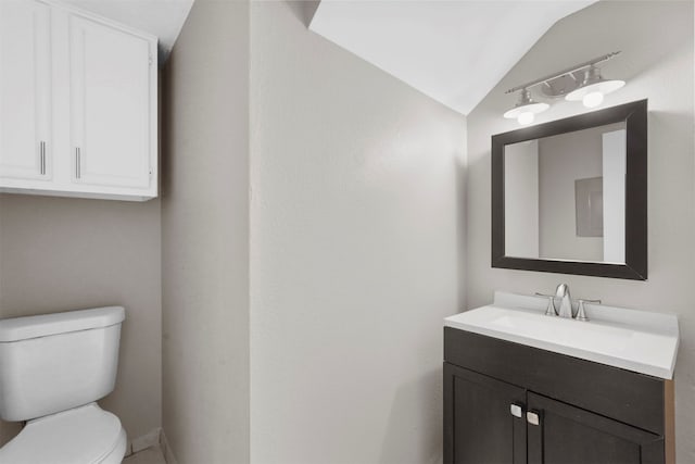 bathroom with vanity, lofted ceiling, and toilet