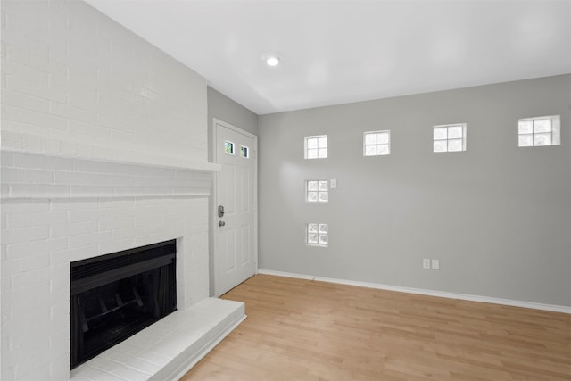 unfurnished living room with a brick fireplace and light hardwood / wood-style flooring