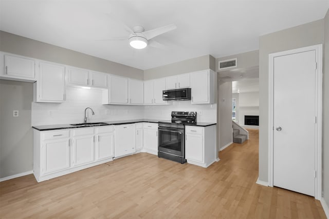 kitchen with sink, white cabinets, light wood-type flooring, and appliances with stainless steel finishes